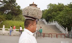 Китаєць, щоб схуднути, гуляє з 40-кілограмовим каменем на голові
