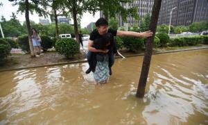 Китаянка перенесла свого бойфренда через затоплену зливами вулицю (фото)
